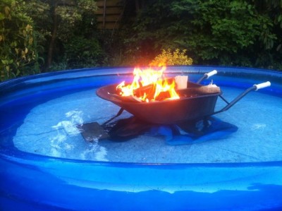 wheelbarrow burning wood in a pool